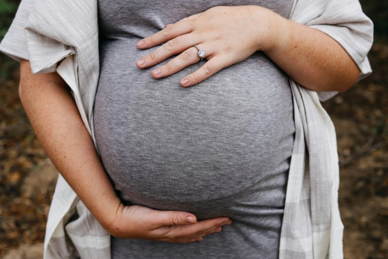Schwangere Frau hält ihre Hände liebevoll um ihren Babybauch