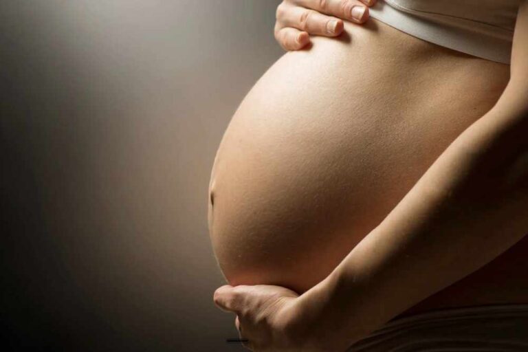 Schwangere Frau haelt liebevoll ihren Babybauch