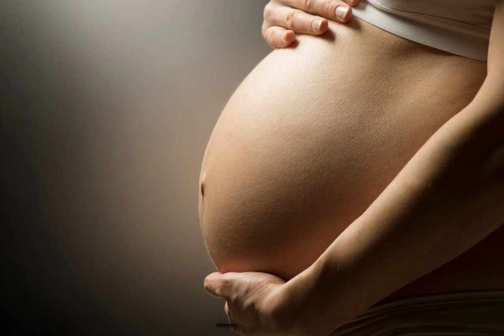 Schwangere Frau haelt liebevoll ihren Babybauch
